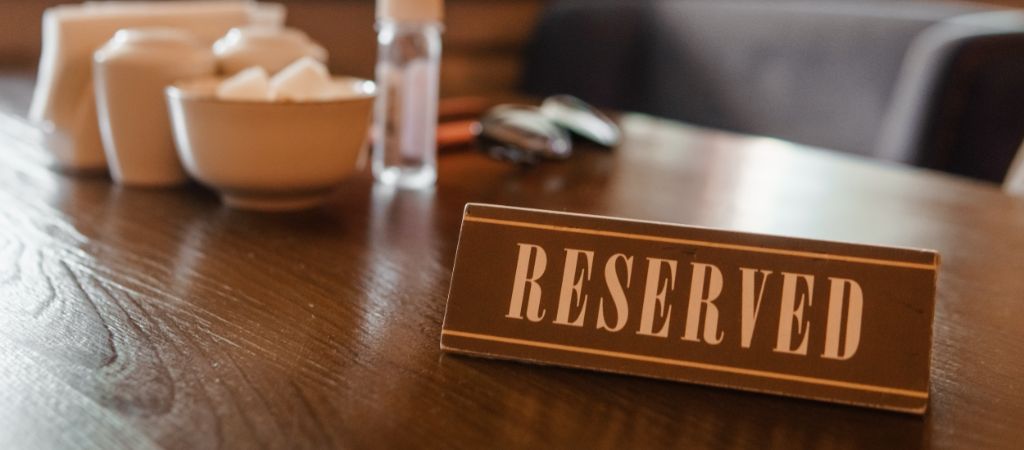 A reserved sign sits on a wooden restaurant table. Reserved Sign on a Restaurant Table