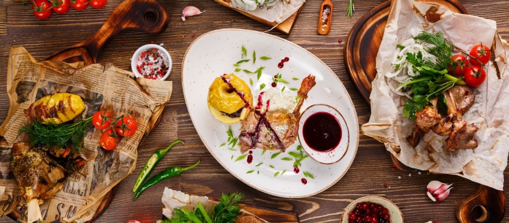 An overhead shot of several dishes on a wooden table, ready to serve at a restaurant. Restaurant Food on a Wooden Table