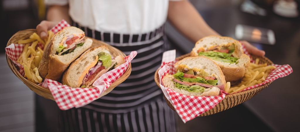 Waitress Serving Sandwiches Mid Waist A waitress serves baskets of sandwiches and fries, taken from the waist.
